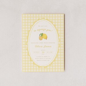 May include: A baby shower invitation with a yellow gingham background. The invitation features an oval design with a lemon illustration and the text "We can't wait to squeeze you!" The invitation is for Olivia James, August 30, 2023.