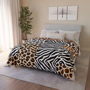 May include: A luxurious blanket with a bold animal print design. The blanket showcases a mix of leopard spots, zebra stripes, and giraffe patterns in brown, black, and white. The blanket is displayed on a bed with white pillows.