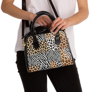 May include: A black and animal print handbag with a top handle and a shoulder strap. The bag features a patchwork design with zebra, leopard, and giraffe patterns. The bag has black accents and gold-coloured hardware.