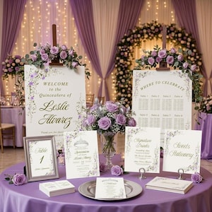 May include: A collection of event stationery for a Quinceañera, including a welcome sign, seating chart, table number, menu, and guest book, all featuring purple floral accents and gold text on white cardstock, arranged on a purple tablecloth.