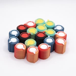 Peut inclure: Un ensemble d'objets cylindriques colorés, chacun avec un dessus circulaire blanc et une petite poignée incurvée. Les objets sont de différentes couleurs, notamment rouge, orange, bleu, jaune et noir. Ils sont disposés en grappe.