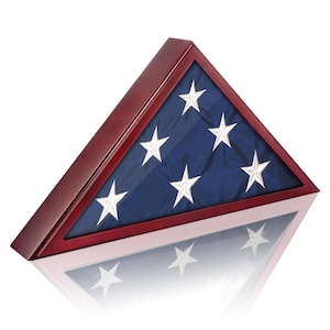 May include: A triangular wooden flag display case with a dark cherry finish. The case holds a folded American flag with white stars on a blue field. The flag is displayed behind a glass panel.