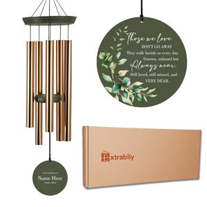 May include: A wind chime with bronze-colored tubes and a dark green top and bottom. A round, dark green pendant with the text "Those we love" and a box with the "Extrabily" logo are also shown.