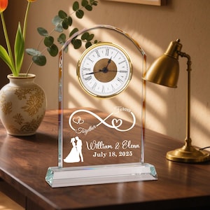 May include: A clear glass clock with a gold-colored clock face and Roman numerals. The clock features the words "Together Forever" and the names "William & Elena" with a date. The clock is a wedding or anniversary gift.