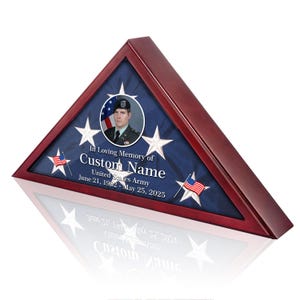 May include: A triangular wooden flag display case with a red-brown finish. Inside, a blue background features white stars and small American flags. The text reads "In Loving Memory of Custom Name, United States Army, June 21, 1962 - May 25, 2025."