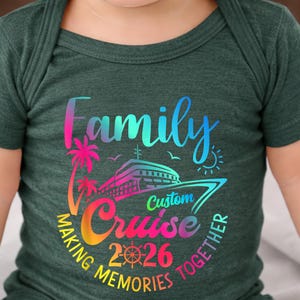 May include: Dark green baby bodysuit with a colourful graphic. The graphic includes the words "Family Cruise 2026" with a cruise ship, palm trees, and the phrase "Making Memories Together."