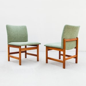 Peut inclure: Deux chaises en bois avec assises et dossiers rembourrés vert clair. Les chaises ont un design simple, de style moderne du milieu du siècle, avec une assise et un dossier rectangulaires et un cadre en bois.