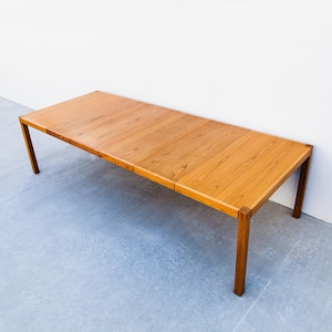 May include: A rectangular wooden table with a light brown finish. The table has four legs and a long, flat surface. The table is approximately 72 inches long and 30 inches wide.