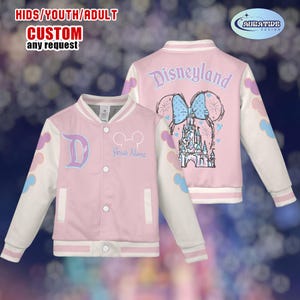 May include: Pink and white custom varsity jacket with the text "Disneyland" on the back and a "D" on the front. The jacket features a Mickey Mouse design and the text "Your Name". The sleeves have colorful cloud accents. The text "KIDS/YOUTH/ADULT CUSTOM any request" is at the top.
