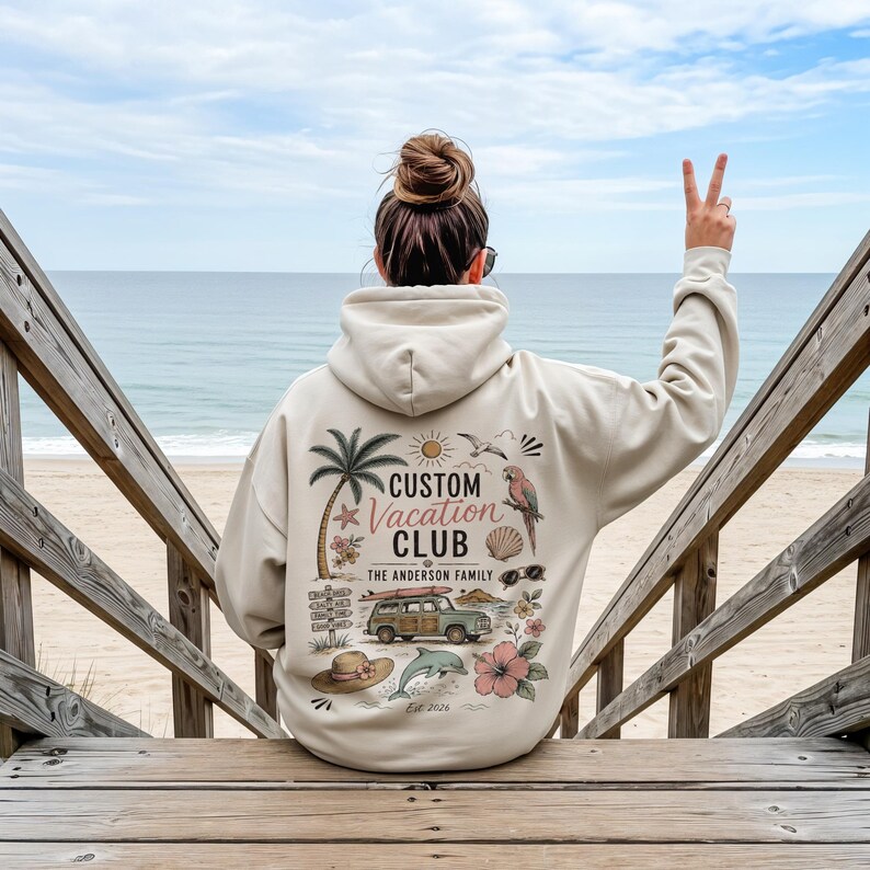 May include: A beige hooded sweatshirt featuring a back graphic with a palm tree, a parrot, a station wagon with a surfboard, a dolphin, a sun, a seashell, a hat, and flowers. The text reads Custom Vacation Club, The Anderson Family, and Est. 2026.