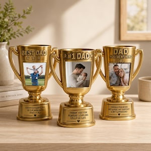 Puede incluir: Tres trofeos dorados con fotos personalizadas. Los trofeos tienen las palabras "BEST DAD", "#1 DAD" y "DAD YOU'RE MY HERO" grabadas. Cada trofeo tiene una base con un mensaje. Un regalo reflexivo para el Día del Padre.
