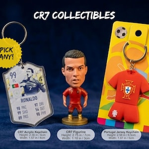 May include: Collection of CR7 collectibles, including an acrylic keychain with a player card design, a figurine, and a Portugal jersey keychain. The figurine is 2.75 inches tall. The acrylic keychain is 2.36 inches tall. The jersey keychain is 2.56 inches tall. The text "PICK ANY!" is on a yellow sticker.