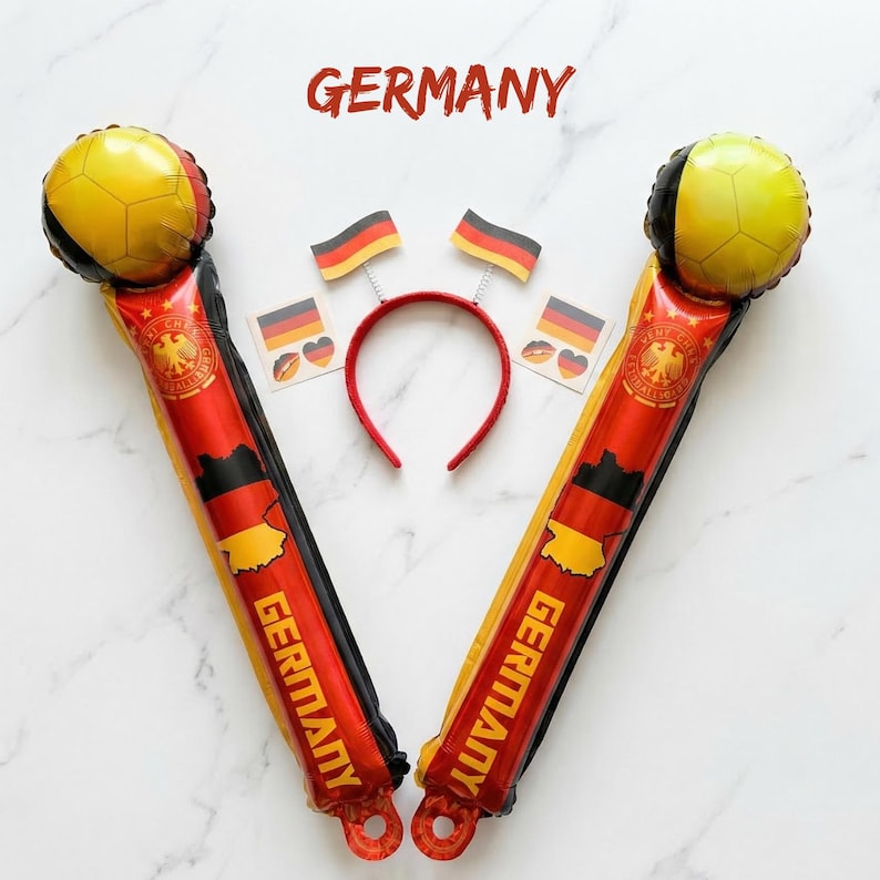 Puede incluir: Dos bastones de animaci&oacute;n inflables con los colores de la bandera alemana negro, rojo y oro, con la palabra GERMANY impresa verticalmente. Incluye una diadema roja con dos peque&ntilde;as antenas de bandera y dos pegatinas cuadradas con motivos.