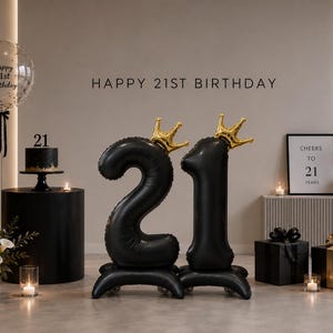 May include: A celebratory scene with black balloons forming the number 21, topped with gold crowns. A small cake, gifts, and a framed print that reads "Cheers to 21 Years" are also present. The words "Happy 21st Birthday" are written across the top.