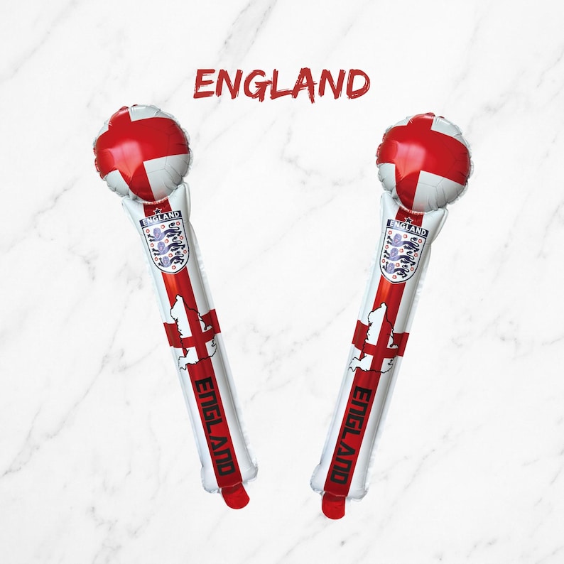 Puede incluir: Dos bastones de animaci&oacute;n inflables con el dise&ntilde;o de la bandera de Inglaterra, una parte superior redonda, el escudo de la selecci&oacute;n nacional de Inglaterra, un mapa de Inglaterra y la palabra ENGLAND impresa en negro. El texto ENGLAND aparece arriba.