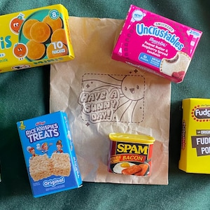 May include: A collection of miniature food items, including Eggo Minis pancakes, Pringles, Rice Krispies Treats, Spam with bacon, Uncrustables peanut butter and jelly sandwiches, and Fudgsicle fudge pops. A brown paper bag with the text "Have a Sunny Day!" is also present.
