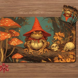 Op de afbeelding: Een fantasievolle speelmat met een kikker met een rode tovenaars hoed en sjaal, zittend op een boomstam in een bos. De mat bevat paddenstoelen, schedels en een set dobbelstenen. Een stapel bijpassende kaarthoezen is ook zichtbaar.