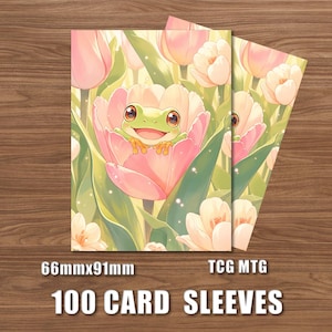 May include: A set of 100 card sleeves measuring 66mm x 91mm for TCG MTG, featuring a graphic illustration of a green frog with large eyes sitting inside a large pink tulip surrounded by other pink and white tulips and green leaves.