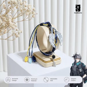 Op de afbeelding: Een handgemaakte armband met een gevlochten ontwerp in marineblauw, geel en lichtblauw. De armband heeft zilveren veersieraden en een zwarte kralen hanger. De woorden "Exclusive Design", "Premium Material", "Adjustable Size" en "Elegant Charm" zijn zichtbaar.