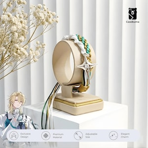 May include: A bracelet with a star-shaped charm featuring a central gemstone. The bracelet has a braided design with white, teal, and gold strands. It is displayed on a beige stand with gold trim. The image also includes the text "Exclusive Design", "Premium Material", "Adjustable Size", and "Elegant Charm".