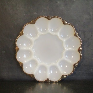 Puede incluir: Plato para huevos de vidrio blanco lechoso con borde dorado. El plato tiene 12 hendiduras individuales para servir huevos.