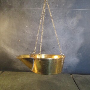 May include: A brass hanging scale with a round bowl. The scale is suspended from a chain.