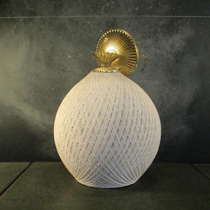 May include: Vintage wall sconce featuring a spherical, off-white woven shade. The light fitting has a gold-coloured, decorative backplate and a small, ornate top. The shade is made of a tightly woven material.