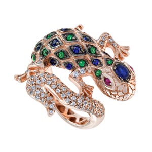 Puede incluir: Un anillo de oro rosa con forma de lagarto, con la cola y el cuerpo incrustados de diamantes. El dorso presenta un patrón de rombos con piedras azules y verdes alternas, un ojo de piedra azul grande y una pequeña piedra de color rojo.