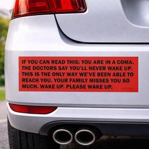 May include: A red bumper sticker with black text, affixed to the rear of a silver car. The text reads: "IF YOU CAN READ THIS: YOU ARE IN A COMA...WAKE UP. PLEASE WAKE UP."