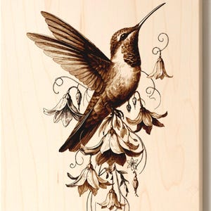 May include: A wood-burned art piece featuring a hummingbird with outstretched wings, depicted in shades of brown. The bird is surrounded by detailed floral elements, all set against a light-colored wooden background. The artwork is mounted on a rectangular wooden panel.