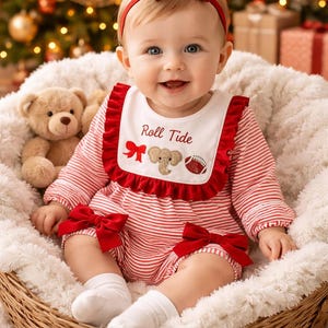 May include: A red and white striped long-sleeve romper featuring a white bib with red ruffles, embroidered with the text Roll Tide, a red bow, an elephant, and a football. The outfit includes red bows on the legs and a matching red headband.