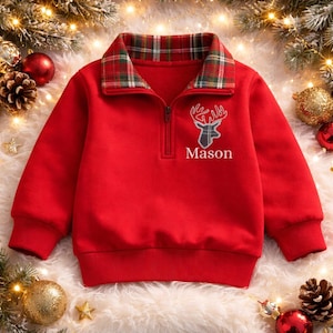 May include: A bright red quarter-zip sweatshirt featuring a plaid collar in red, green, and white. The chest displays an embroidered gray plaid deer head silhouette above the white text Mason, with long sleeves and ribbed cuffs.