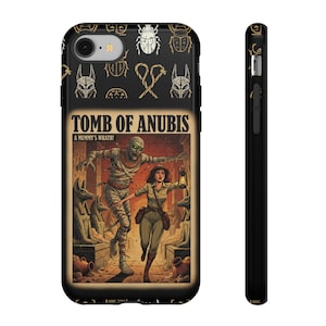 Puede incluir: Funda de teléfono negra con un diseño de portada de cómic vintage. La portada muestra una momia persiguiendo a una mujer con una linterna, con el texto "TOMB OF ANUBIS" y "A MUMMY'S WRATH!". La parte superior de la funda tiene escarabajos y jeroglíficos dorados.