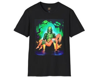Könnte beinhalten: Schwarzes T-Shirt mit einem grafischen Aufdruck einer Kreatur aus der schwarzen Lagune, die eine Frau hält. Das Bild hat ein grünes, blaues und oranges Farbschema. Das T-Shirt ist aus einem weichen Material gefertigt.