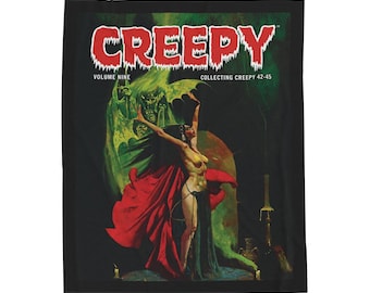 May include: Black throw blanket featuring the word "CREEPY" in red, with a vintage comic book cover design. The artwork depicts a woman in a red cape with a green monster in the background. The text "VOLUME NINE" is also visible.