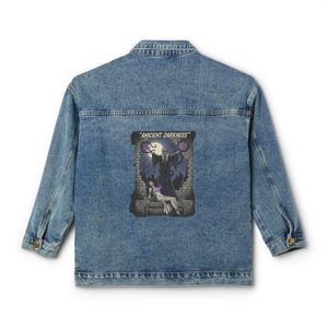 May include: A light blue denim jacket with a graphic on the back that reads "ANCIENT DARKNESS". The graphic shows a dark figure, a seated person, and a full moon. The jacket has a classic collar, button closure, and two chest pockets.