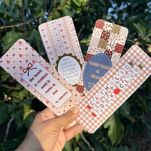 May include: Four rectangular bookmarks with rounded corners featuring autumn-themed patterns. One displays the text 'Our heart is restless until it rests in you - St. Augustine', another 'Have patience with all things', 'EVERYTHING IS GRACE', and 'CATHOLIC BOOK CLUB'.