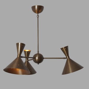 May include: A mid-century modern chandelier with a bronze finish. The fixture features four cone-shaped shades with small perforations, a central sphere, and a ceiling mount. The light fixtures are suspended from a central rod.
