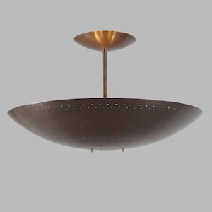 Peut inclure: Un plafonnier de style moderne du milieu du siècle, de couleur bronze. Le luminaire est doté d'un grand abat-jour en forme de bol avec de petites perforations sur le bord. Un auvent circulaire plus petit et une tige centrale se connectent au plafond.