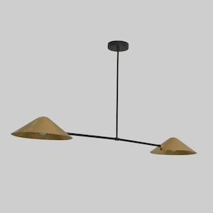 May include: A modern, two-light pendant lamp with a black frame and two conical, gold-colored shades. The lamp hangs from a black ceiling mount, offering a minimalist design for interior lighting.