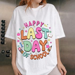 以下が含まれることがあります： 「HAPPY LAST DAY OF SCHOOL」と書かれたカラフルなグラフィックが特徴の白いTシャツ。デザインには星、リンゴ、鉛筆、その他の学校関連のアイコンが含まれています。 ゆったりとしたカジュアルなフィット感のシャツです。