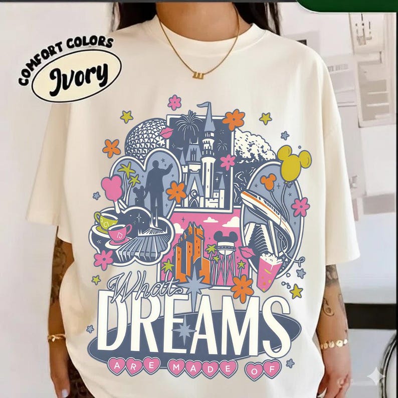 Puede incluir: Camiseta marfil Comfort Colors con un dise&ntilde;o gr&aacute;fico colorido. El dise&ntilde;o presenta un castillo, edificios y el texto "What Dreams Are Made Of". La camiseta tiene cuello redondo y mangas cortas.