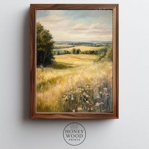 May include: A framed landscape painting depicts a sunlit field of tall grass and wildflowers, with trees on the left and rolling hills in the distance. The artwork is in a wooden frame, and the overall color palette is warm and inviting.