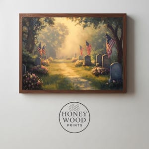 May include: A framed print of a cemetery scene with American flags and headstones. The artwork depicts a path leading through the graves, with sunlight filtering through the trees. The print is in a dark brown wooden frame.