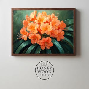 Könnte beinhalten: Ein gerahmter Blumendruck mit einem Cluster aus orangefarbenen Blüten mit langen Staubgefäßen, vor einem Hintergrund aus grünen Blättern und einem dunkelgrünen Hintergrund. Das Kunstwerk befindet sich in einem braunen Holzrahmen. Das Honey Wood Prints-Logo befindet sich unten.