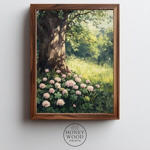 May include: A framed art print showing a tranquil scene of a tree and pink flowers in a meadow. The artwork is set in a green meadow, with sunlight filtering through the leaves. The frame is made of dark wood. The print is from Honey Wood Prints.