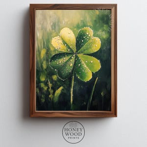 May include: A framed artwork featuring a four-leaf clover with water droplets. The clover is painted in shades of green and yellow, set against a blurred green background. The frame is made of wood. The artwork is from Honey Wood Prints.