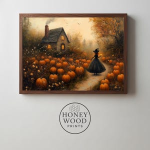 May include: A framed wall art print depicting a stone cottage with a smoking chimney nestled in a pumpkin patch. A figure in a black dress and pointed hat walks along a path holding a lantern. The scene features orange pumpkins and autumn trees.