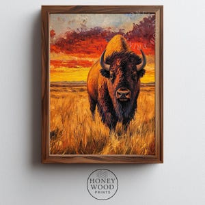 May include: A framed painting of a bison in a field of tall grass under a vibrant sunset. The bison is brown with large horns and a shaggy mane. The sky is a mix of orange, red, and yellow hues, creating a dramatic backdrop.