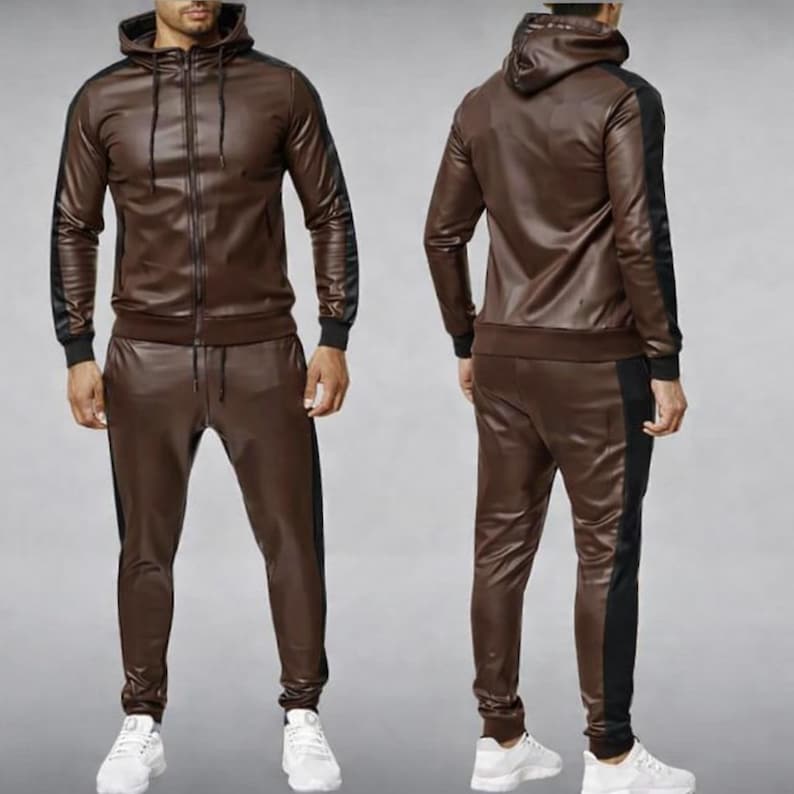 May include: A brown faux leather tracksuit featuring a hooded zip-up jacket and matching pants. The jacket and pants have black stripes down the sides. The tracksuit is a two-piece set.